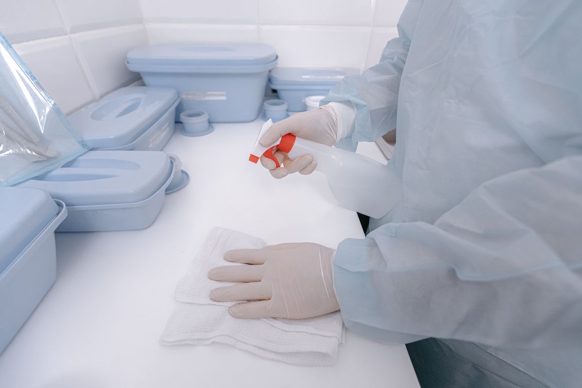 Close-up of gloved hands disinfecting a surface in a clinical setting